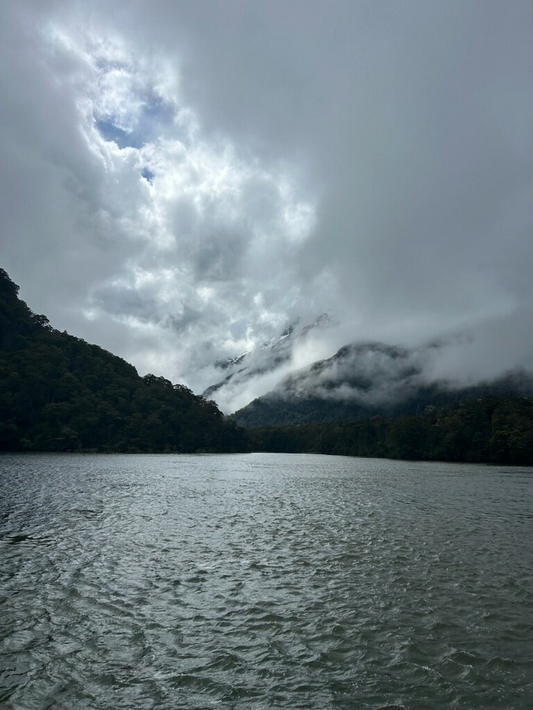 Mist clinging to mountain slopes above lake on the Routeburn Track in moody weather