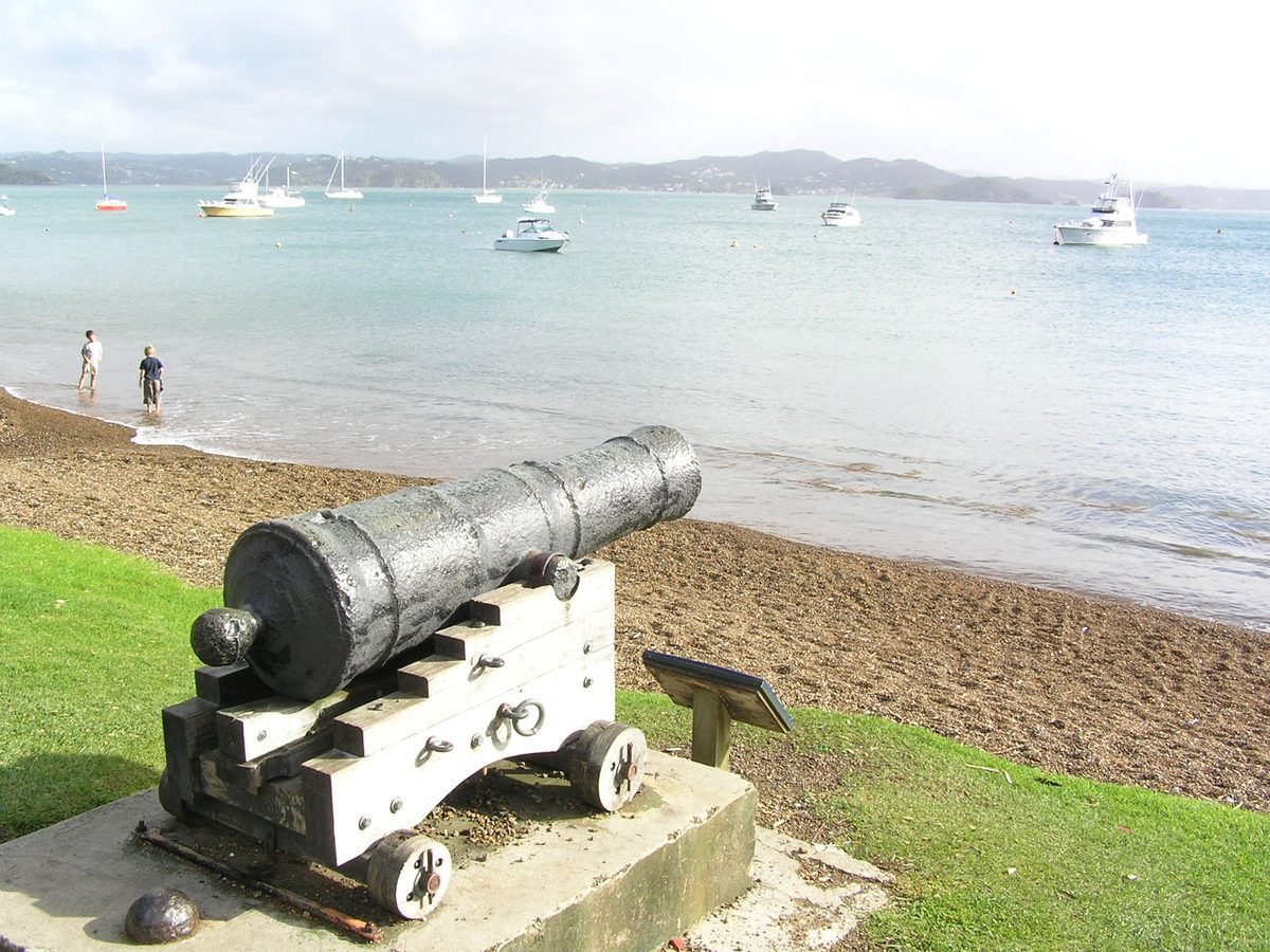 Historic cannon on Russell waterfront overlooking Bay of Islands harbour and boats Northland New Zealand