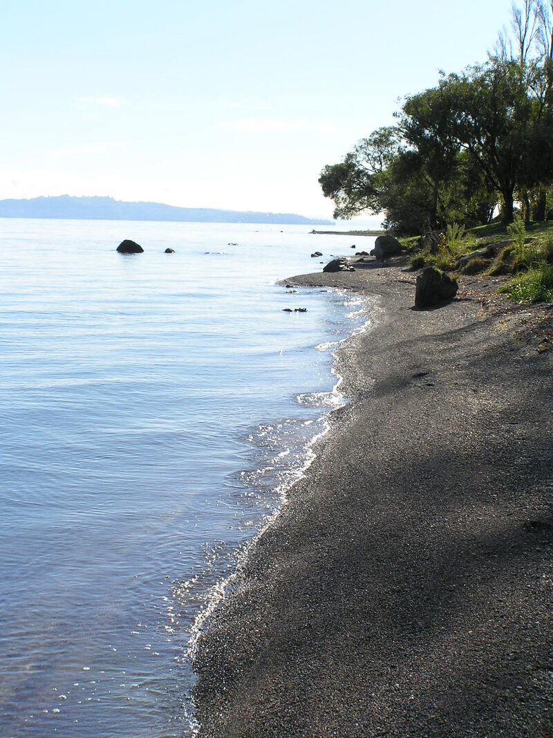 Lake Taupō shoreline with calm water and mountains in the distance New Zealand