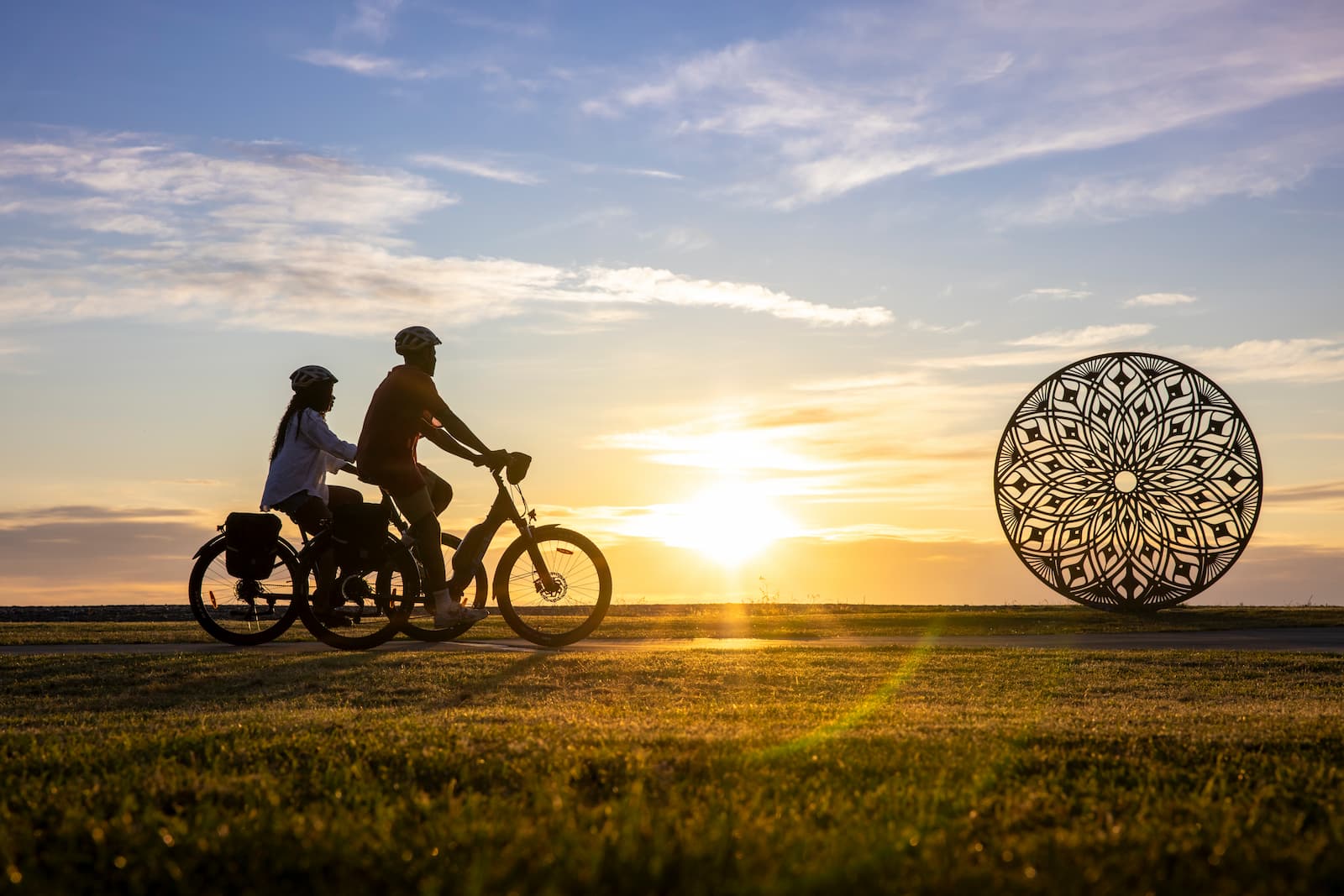 Couple cycling at sunset past sculpture on the Hawkes Bay cycle trail Napier